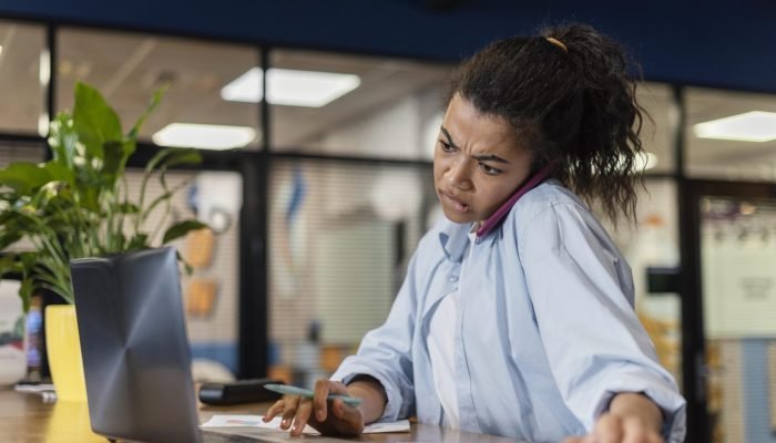 stressed-woman-office-using-laptop-talking-smartphone.jpg